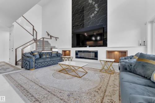 Two-story living area featuring a prominent black stone-finish accent wall with a built-in electric fireplace - 16816 49 Street, Edmonton, AB 