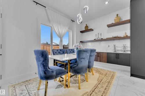 Dining area with contemporary overhead lighting, large glass doors, and white tile flooring - 16816 49 Street, Edmonton, AB 