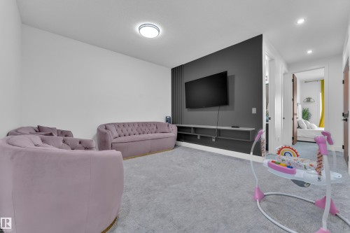 Spacious room with light gray carpeting and a contrasting dark accent wall - 16816 49 Street, Edmonton, AB 