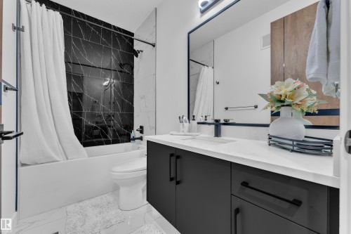 Modern bathroom featuring a deep soaking tub with a black marble-patterned tile surround - 16816 49 Street, Edmonton, AB 