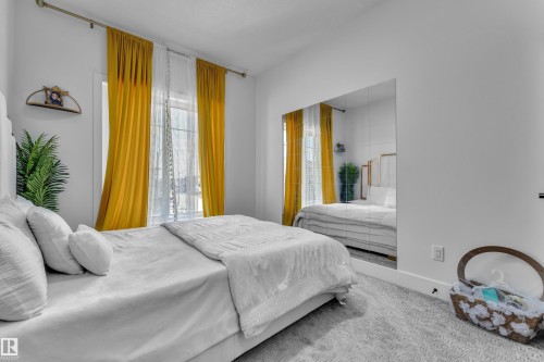 Bright room featuring a full wall of mirrored panels, a window with sheer and solid drapes, and light-toned carpeting - 16816 49 Street, Edmonton, AB 