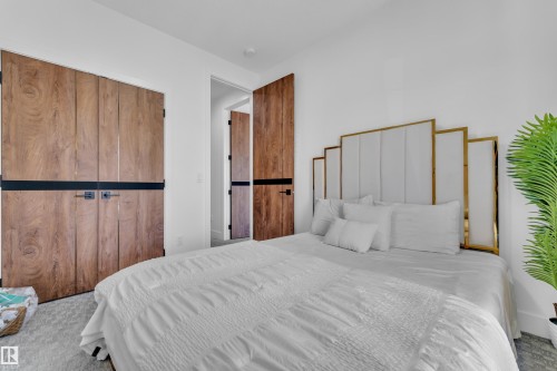 Bedroom featuring light wood-finish doors with horizontal black banding, white walls, and light-toned carpet flooring - 16816 49 Street, Edmonton, AB 