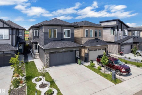 Contemporary two-story residence featuring a dark gray and light gray siding exterior with stone accents - 16816 49 Street, Edmonton, AB 