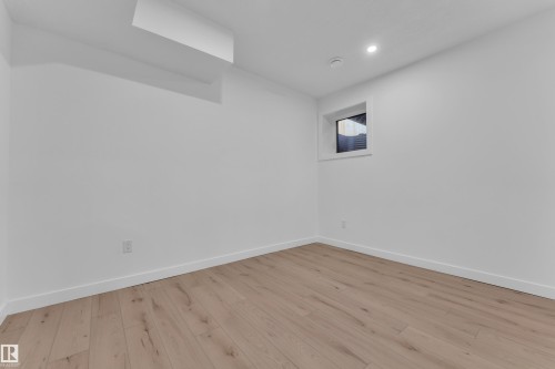 Room featuring light wood-finish flooring, white walls, recessed ceiling lighting, and a high window with blinds - 16816 49 Street, Edmonton, AB 