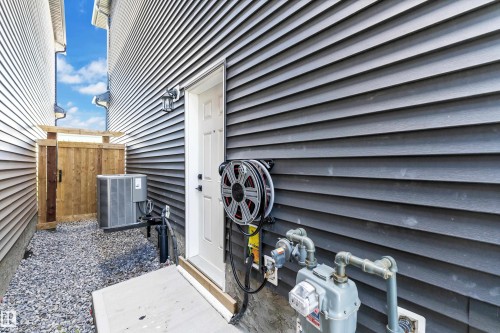 Dark gray horizontal siding with a white utility door and exterior lighting fixture - 16816 49 Street, Edmonton, AB 