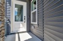 Entryway featuring a white door with an integrated glass panel, dark horizontal siding, and a partial stone facade - 16816 49 Street, Edmonton, AB 