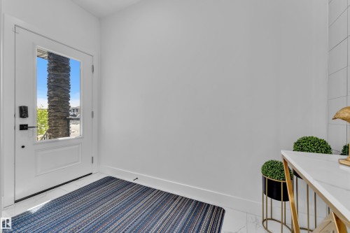 Entryway featuring a white paneled door with a clear glass insert, matte black hardware, and white baseboards - 16816 49 Street, Edmonton, AB 