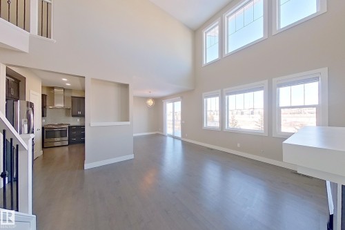 Two-story living area featuring wood-finish flooring, a vaulted ceiling, and multiple windows - 4343 Crabapple Crescent, Edmonton, AB 