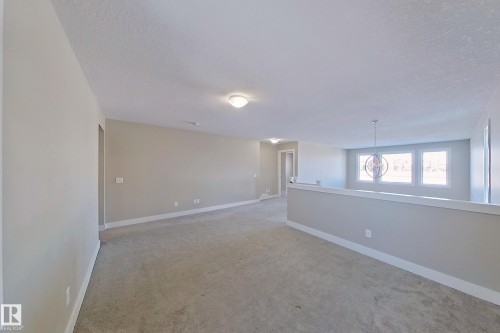 Open loft area with neutral-toned carpet and light gray walls - 4343 Crabapple Crescent, Edmonton, AB 
