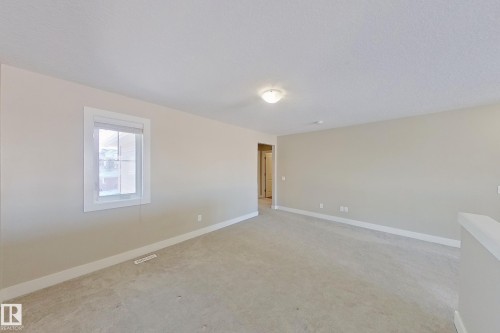 Spacious room featuring neutral carpeting, a single window with white trim, and a flush-mount ceiling light fixture - 4343 Crabapple Crescent, Edmonton, AB 
