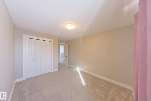 Carpeted room featuring a white bi-fold door closet, neutral wall paint, and white trim - 4343 Crabapple Crescent, Edmonton, AB 