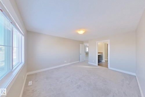 Spacious room featuring neutral carpeting, light-toned walls, and a large window - 4343 Crabapple Crescent, Edmonton, AB 