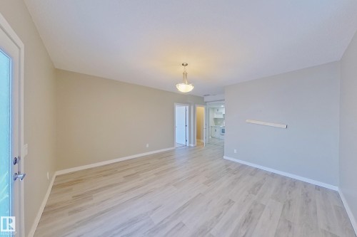 Spacious room with wood-finish flooring, neutral paint palette, contemporary semi-flush ceiling light fixture, and white baseboards - 4343 Crabapple Crescent, Edmonton, AB 