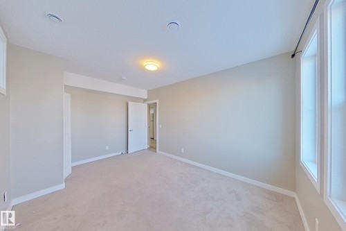 Spacious room featuring neutral carpeting, light-toned walls, and white trim - 4343 Crabapple Crescent, Edmonton, AB 