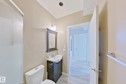 Bathroom featuring a dark wood-finish vanity with an integrated sink, framed mirror, and chrome fixtures - 4343 Crabapple Crescent, Edmonton, AB 