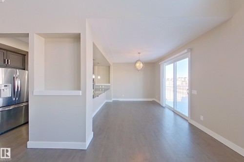 Spacious interior featuring wood-finish flooring, a built-in wall niche, and a contemporary chandelier - 4343 Crabapple Crescent, Edmonton, AB 