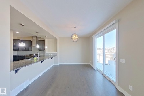 Open-concept dining area featuring wood-finish flooring, a contemporary chandelier, and a sliding glass door providing access to an exterior balcony - 4343 Crabapple Crescent, Edmonton, AB 