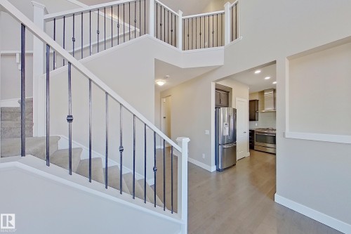 Two-story foyer with carpeted staircase, white railing, and dark metal balusters - 4343 Crabapple Crescent, Edmonton, AB 