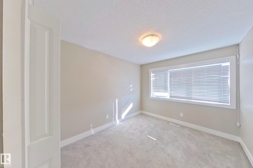 Neutral-toned room featuring a single window with blinds, light-colored carpeting, a white baseboard, and a ceiling-mounted light fixture - 4343 Crabapple Crescent, Edmonton, AB 