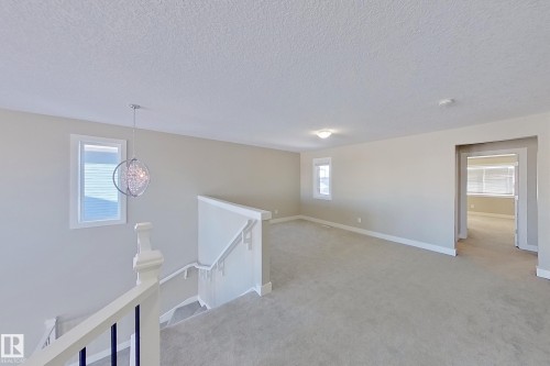 Bright upper-level landing featuring neutral carpeting, light-toned walls, and white trim - 4343 Crabapple Crescent, Edmonton, AB 