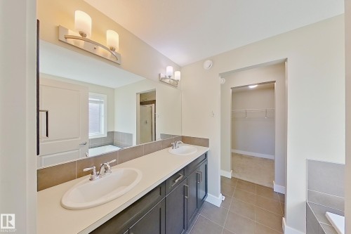 Dual vanity with white undermount sinks and chrome faucets, set into a light countertop with a tile backsplash - 4343 Crabapple Crescent, Edmonton, AB 