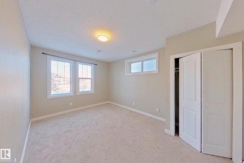 Carpeted interior room featuring neutral wall tones, white trim, and a ceiling-mounted light fixture - 4343 Crabapple Crescent, Edmonton, AB 