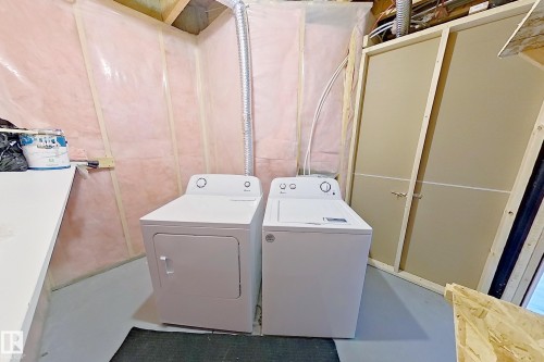 Dedicated laundry area featuring a white washing machine and dryer, a white countertop, and exposed pink insulation - 4343 Crabapple Crescent, Edmonton, AB 