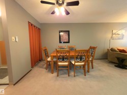 Dining area featuring a ceiling fan with light fixture, carpet flooring, and neutral wall tones - 