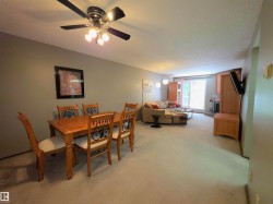 Open-concept living space featuring neutral carpet flooring, a ceiling fan with integrated lighting, and a sliding glass door leading to exterior - 
