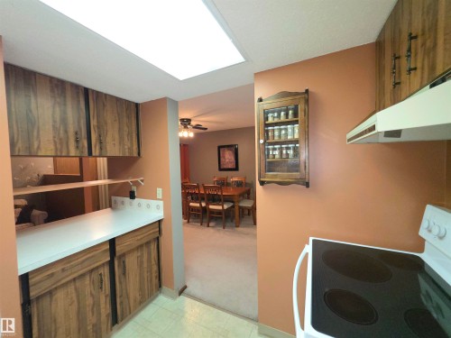Kitchen featuring wood-finish cabinetry, white countertops, and white appliances including an electric range with a range hood - 302 10335 118 Street, Edmonton, AB 