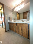 Dual vanity with wood-finish cabinetry, integrated sinks, and a large wall-mounted mirror - 
