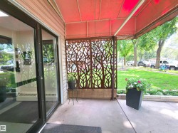 Inviting entryway featuring a red awning, decorative tree-patterned screen, light-colored siding, concrete flooring, and a large glass entry door - 