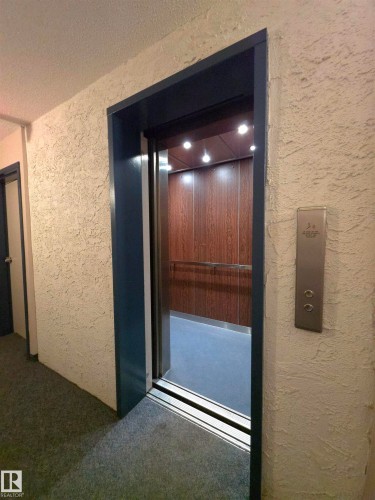 Elevator access featuring wood-finish interior walls and recessed lighting - 302 10335 118 Street, Edmonton, AB 