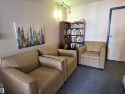 Carpeted area featuring a corner bookcase and three upholstered armchairs - 