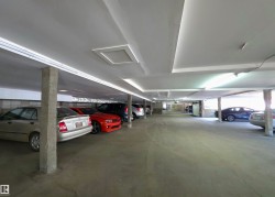 Underground parking garage featuring concrete pillars, fluorescent lighting, and recessed ceiling panels - 