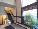Lobby area featuring a wide staircase with dark blue handrails and carpeted treads, alongside a large window with plaid window treatments - 302 10335 118 Street, Edmonton, AB 