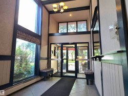 Two-story foyer featuring a chandelier, large windows with patterned shades, tiled flooring, and a glass-paneled entry door - 