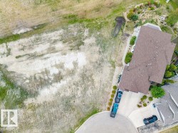Expansive undeveloped lot with partial green growth, bordering a paved cul-de-sac - 