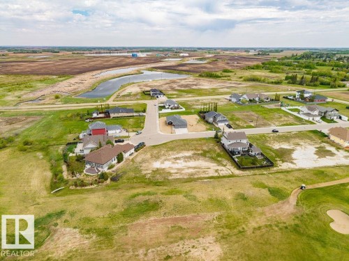 Residential development featuring established homes and undeveloped lots, surrounded by green spaces and a water feature - 25 Whitetail Green, Mundare, AB 