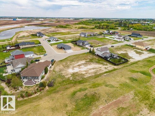 Aerial perspective showcasing a residential development with established homes and undeveloped lots - 25 Whitetail Green, Mundare, AB 