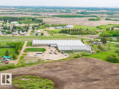 Large-scale greenhouse facility featuring multiple connected structures, extensive glass paneling, and a substantial parking area - 25 Whitetail Green, Mundare, AB 