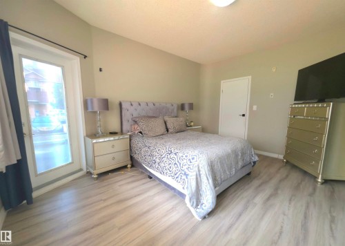 Spacious room featuring light wood-finish flooring, a full-lite exterior door, and a vaulted ceiling - 104 4312 139 Avenue, Edmonton, AB 