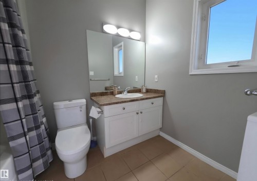 Bathroom featuring a white vanity with a brown countertop, white commode, and an operable window - 104 4312 139 Avenue, Edmonton, AB 