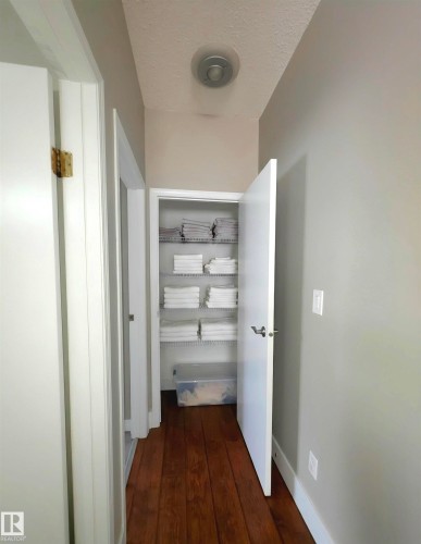 Hallway with rich wood-finish flooring, light gray wall paint, and white trim - 104 4312 139 Avenue, Edmonton, AB 
