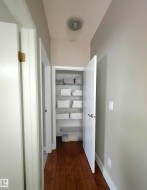 Hallway with rich wood-finish flooring, light gray wall paint, and white trim - 