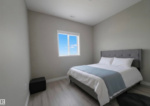 Bright room featuring a window with white trim, light gray walls, and wood-finish flooring - 104 4312 139 Avenue, Edmonton, AB 