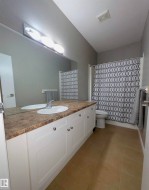 Bathroom featuring a dual-sink vanity with white cabinetry and a patterned countertop - 