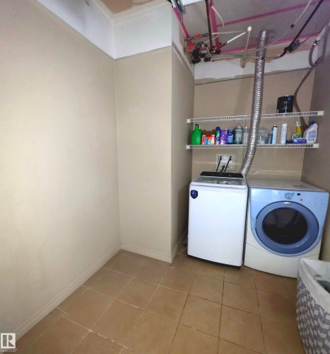Dedicated laundry area featuring ceramic tile flooring, wire shelving, and visible utility connections - 104 4312 139 Avenue, Edmonton, AB 
