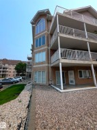 Multi-story building exterior featuring brick-finish siding and multiple balconies with white railings - 