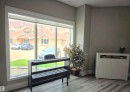 Spacious room featuring a wide window with white trim, wood-finish flooring, and light-toned walls - 104 4312 139 Avenue, Edmonton, AB 